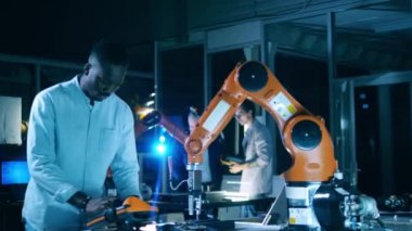 Esmer tenli mühendis robotlara karmaşık görevleri yerine getirmeyi öğretiyor. Yenilik, teknoloji kavramı.