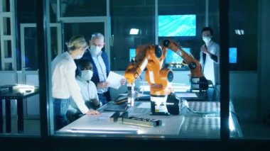 Robot geliştirme laboratuvarında çalışan maskeli mühendisler. Yenilik, teknoloji kavramı.