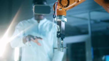 Mühendis jestleri ve VR teknolojisiyle kontrol edilen robot kol. VR, fütürist, sanal gerçeklik kavramı.