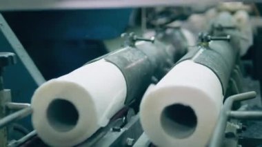 Fabrika makinesi tuvalet kağıdı rulolarını kesiyor.