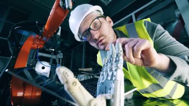 Vedere cu unghi scăzut a inginerului cu laptop care examinează mâna bionică — Videoclip de stoc