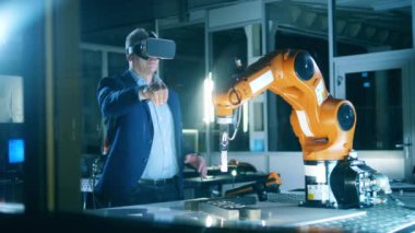 VR, fütüristik, sanal gerçeklik kavramı. Laboratuvarda VR kulaklık takan mühendis robotları test ediyor.