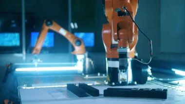 Turuncu robotik kol mikroçipi alıp başka bir yere götürüyor.