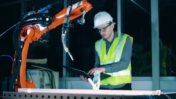 Engineer in helmet and uniform programming arc welding robot — Stock Video