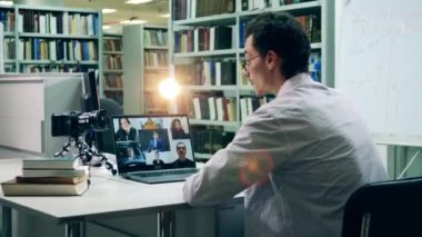 Profesör uzaktan bilgisayar kullanarak ders veriyor.