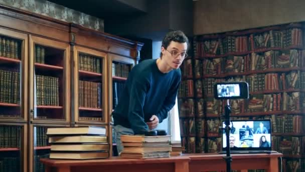 Férfi tanár, aki távolról vezeti a leckét egy könyvtárból. — Stock videók