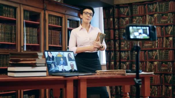 Обучающая женщина проводит онлайн-урок с книгой в руках — стоковое видео