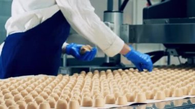 Fabrika işçisi şekerleri taşıyıcıdan kaldırıyor.