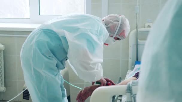 El médico con un traje de materiales peligrosos está inyectando a un paciente. — Vídeos de Stock