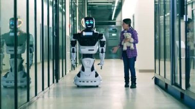 Oyuncak ayılı bir kız bir sayborgla konuşuyor. İnsan ve robot iletişimi.