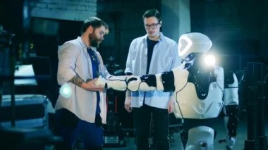 İki mühendis bir cyborgu kontrol ediyor. Robot laboratuarı, robotla çalışan mühendisler..