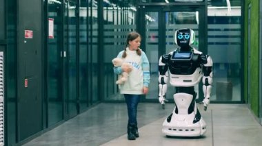 İnsan ve robot iletişimi. Cyborg elinde oyuncak ayıyla genç bir kızla sohbet ediyor.