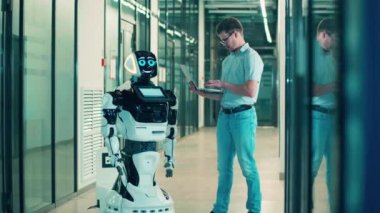 İnsan ve robot birlikte çalışıyor. Bilişim uzmanı dizüstü bilgisayarı olan bir cyborgu yönetiyor.