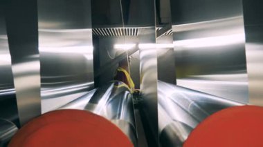 Erkek işçi metal panellerin taşındığını gözlemliyor.