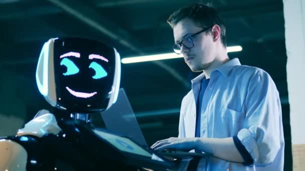 Hombre especialista con un ordenador portátil está observando un cyborgRobotic laboratorio, ingenieros eorking con robot. — Vídeo de stock