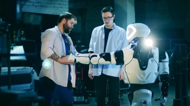 Dos ingenieros están comprobando un cyborg. Laboratorio robótico, ingenieros trabajando con robot. — Vídeo de stock