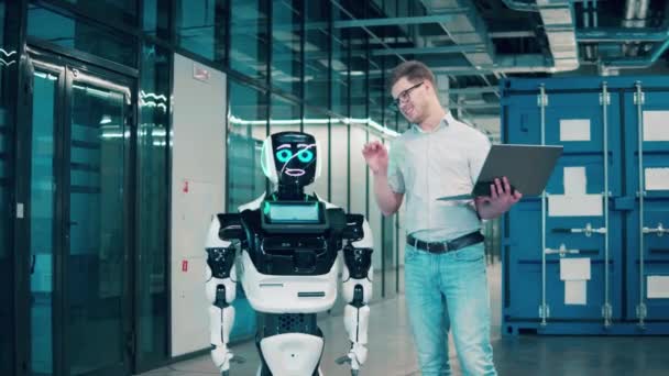 人間とロボットが一緒に働く。男性エンジニアは人間のようなロボットと話しています — ストック動画