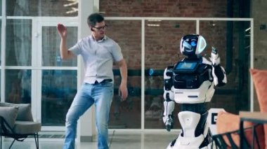 Bir adam insan benzeri bir robota dans etmeyi öğretiyor. Gelecekçi cyborg, yenilikçi robot konsepti.