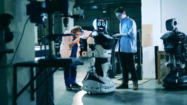 Modern robot iki erkek mühendis tarafından inceleniyor. Gelecekçi cyborg, yenilikçi robot konsepti. — Stok video