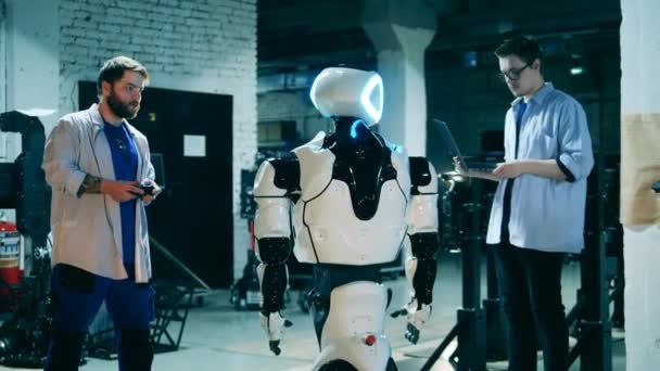Los ingenieros masculinos están operando un robot cibernético con aparatos — Vídeos de Stock