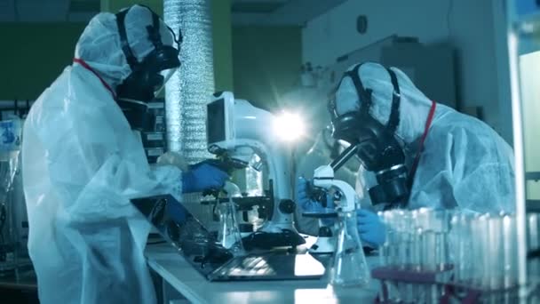 Przeciwciała badają koknept, covid-19 pandemię koronawirusową. Eksperci od kombinezonów ochronnych analizują próbki chemiczne. — Wideo stockowe