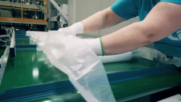 Fabriek werknemer zet plastic bekers in polyethyleen zakken — Stockvideo