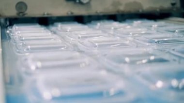 Taşıyıcı bant boyunca ilerleyen plastik paketi kapat