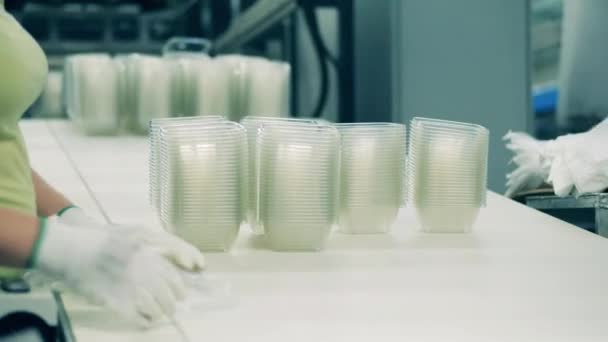 Factory workers are packing plastic containers into polyethylene — Stock Video