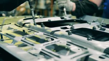 Yapıştırıcı metal bir otomotiv parçasına dökülüyor.