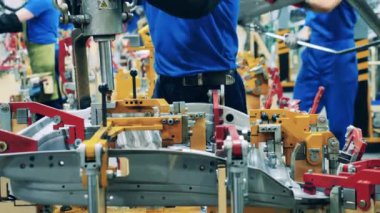 Metal otomotiv elementleri modern endüstriyel fabrikadaki işçiler tarafından kaynak ediliyor..