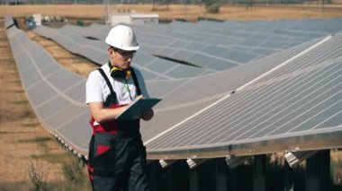 Tamirci güneş panellerine bakıyor ve not alıyor.