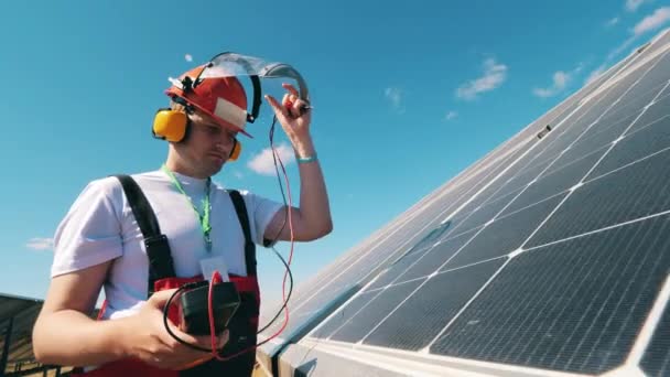 Reparador está usando um dispositivo para verificar a tensão em painéis solares — Vídeo de Stock