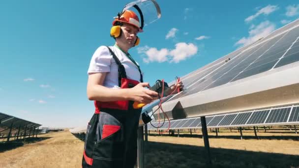 Концепция возобновляемой энергии. Ремонтник проверяет напряжение в наружных солнечных панелях — стоковое видео