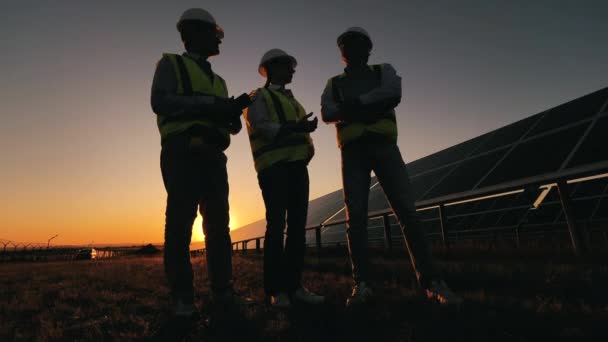 Gli ispettori della sicurezza discutono accanto alle batterie solari al tramonto. Concetto di elettricità rinnovabile. — Video Stock