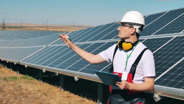 El hombre de mantenimiento está tomando notas cerca de paneles solares — Vídeo de stock
