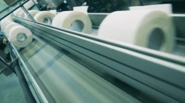 Üretim hattı boyunca ilerleyen tuvalet kağıdı rulolarının yakın çekim