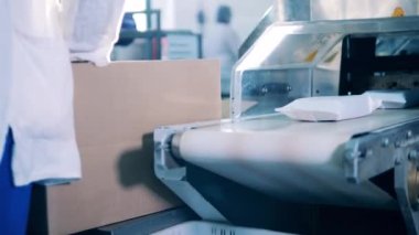 Bir fabrika işçisi küçük paketleri kutulara koyuyor.