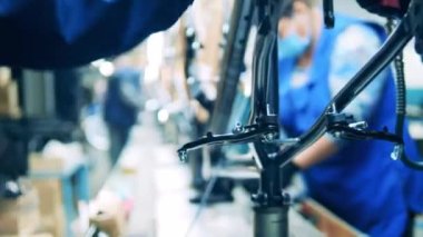 Fabrika işçisi bisiklet gövdesini inceliyor.