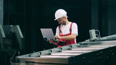 Dizüstü bilgisayarı olan bir erkek çalışan bir taşıyıcının yanında duruyor.