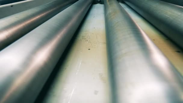 Metal plate on the conveyor and spinning rollers moving it — Video