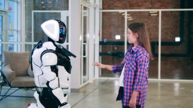 Dost canlısı bir robot ve genç bir kız el ele tutuşuyorlar.