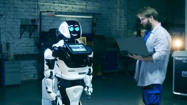 Робототехнік-дослідник з ноутбуком спостерігає за роботоподібною машиною — стокове відео
