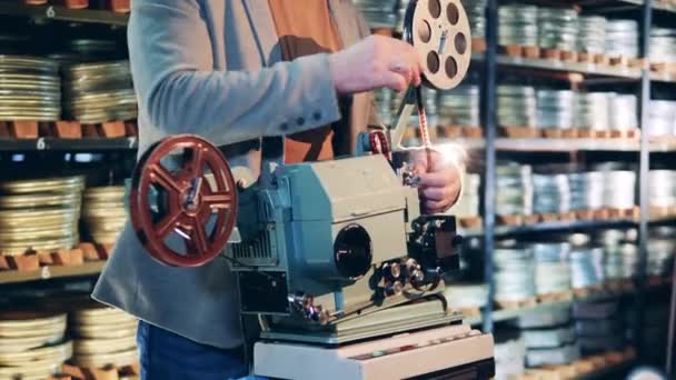 Pracownik archiwum wkłada taśmę filmową do projektora — Wideo stockowe