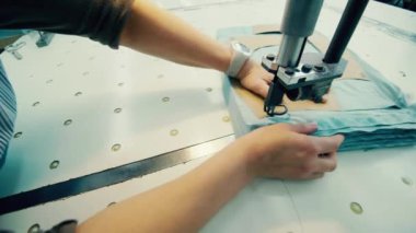 Fabrika işçisi tekstil kesmek için bir şablon kullanıyor.