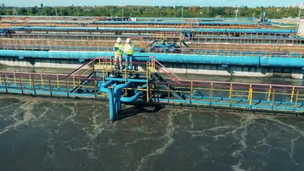Vista aérea de dos trabajadores que observan un sistema de tratamiento de aguas residuales — Vídeos de Stock