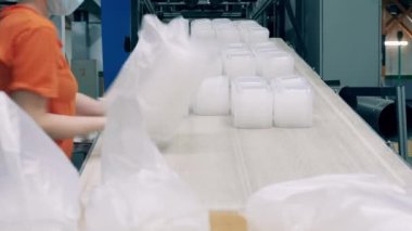 Fabrika işçileri poşetlere plastik paket koyuyorlar.