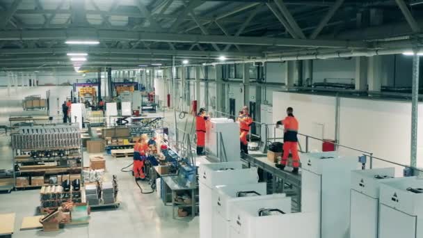 Industriële fabriek assemblagelijn. Medewerkers van de koelfabriek monteren handmatig koelkasten — Stockvideo