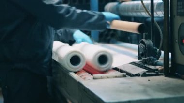 Kağıt fabrikası işçisi özel bir makine kullanarak kağıt rulo yapıyor.