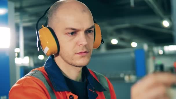 Άνδρας χειριστής με φθορά ασφαλείας και ακουστικά στο χώρο εργασίας — Αρχείο Βίντεο