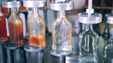 Cam şişeler bir fabrika makinesi tarafından likörle dolduruluyor.